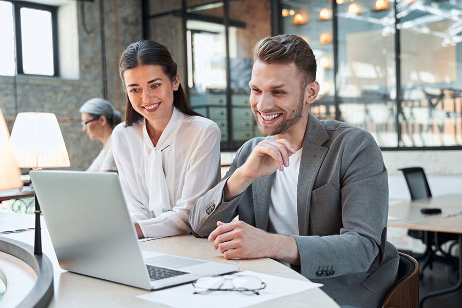 SEO, Werbung: Eine Dame und ein Herr sitzen fröhlich vor dem Laptop und besprechen etwas., Werbung