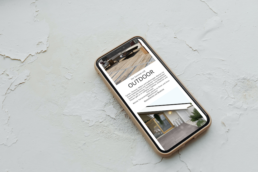 5 einfache KI-Funktionen für effizientes E-Mail-Marketing: Iphone liegt auf einem rauen Untergrund und zeigt den Outdoor Abschnitt einer Webseite.